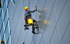 Pomona Cleaning Services employee cleaning large windows on a building